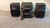 Front view of Panasonic stereo system with 5 CD changer, amplifier/tuner, remote control, and two speakers on carpeted floor.