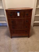 Front view of the antique wooden highboy dresser showing four drawers and antique brass pulls intact.
