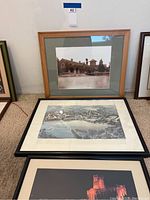 Photo showing three framed pictures stacked vertically on floor including Redlands Library photo at top