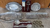 View of multiple Arthur Court silver-tone serving pieces displayed on floor, including trays, utensils, napkin rings, and dish, showing detailed animal and nature motifs.