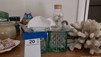 Various glass jars, vases, white coral, seashells, and small decorative items on wooden shelf