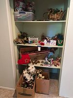 Shelves with various Christmas decorations including figurines, garlands, stockings, and gift boxes in cardboard boxes below.