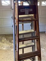 Wooden ladder showing five steps with weathered wood finish and metal support braces