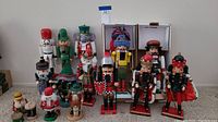 Wide view showing all 14 nutcrackers arranged on carpet and some inside boxes, details of colors, styles and conditions visible.