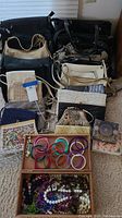 Overview of all purses and costume jewelry including bracelets, beads, and coin purse arranged on floor
