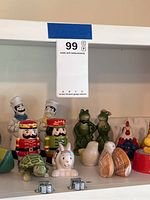Shelf with a variety of character salt and pepper shakers including chefs, frogs, turtle, rabbit, shells, rooster.