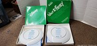 Two Walt Disney plates in green collectible boxes with certificates of authenticity, backs of plates showing Walt Disney branding and edition info.