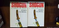 Photo of two hardcover books titled 'Shogun A Novel of Japan' by James Clavell, showing front covers with sword illustration.