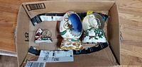 Box containing two Santa-themed snow globes and an ornate Christmas egg-shaped ornament, all in good condition.
