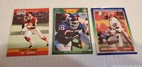 Front view of three football trading cards featuring Derrick Thomas, Lawrence Taylor, and Deion Sanders in action poses.