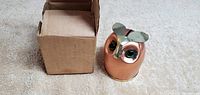 Copper owl figurine next to the original cardboard box, showing front and detail of the item.