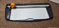 Top view of Fiskars rotary paper trimmer showing cutting grid and orange rotary blade on white rail.