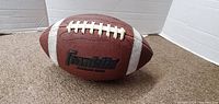 Side view of the Franklin football, showing white laces and one white stripe.