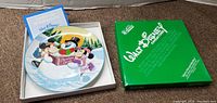 Photo showing the plate inside the box along with the certificate of authenticity and a green box with Walt Disney Characters branding.