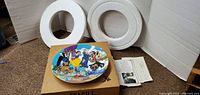 Full view of the collectible plate with styrofoam packaging and original box underneath. Certificate of Authenticity is visible beside the box.