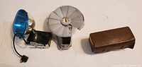 Photo showing vintage flash units and carrying case with accessories, laid out on a flat surface