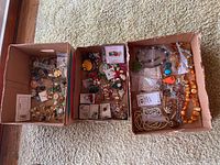 Three open cardboard trays showing mixed jewelry