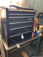 Front view of the black Craftsman 5-drawer tool chest on a metal table, showing the overall condition and size.