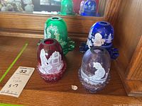 Front view of four Fenton Fairy Light lamps in red, green, blue, purple with lids and tea lights