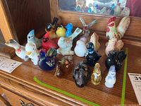 Overview of 20 assorted bird figurines on wooden surface in front of mirror