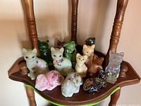 Group shot of fourteen cat figurines on wooden shelving