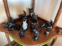 Group shot of all eleven black glass animal figurines on wood shelf