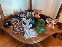 Overview of all 16 Fenton glass animal figurines on wooden surface
