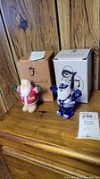 Two Santa Claus glass figures with original Fenton boxes in background