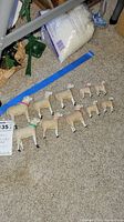 Nine wool-covered wooden sheep figures arranged in three rows