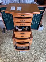 Overview of chest interior showing hanging necklaces and open drawers with jewelry contents