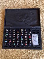 Black hinged storage box open to show foam insert holding 49 rings