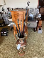Vase containing seven walking sticks in room setting