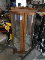 Front view of oak corner curio cabinet with double glass doors and visible wood grain finish.