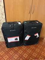 Two black Outbound suitcases side by side showing front with tags and labels attached.
