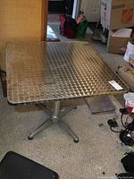 Complete view of the square metal cafe-style table showing textured diamond pattern on the top.