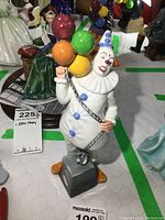 Front view showing the clown holding colorful balloons on a gray base.