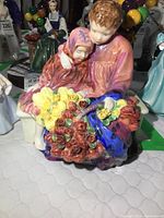 Front view of the Royal Doulton Flower Sellers Children figurine showing two children seated with an arm around and holding colorful flowers.