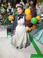 Front view of Royal Doulton Biddy Penny Farthing figurine showing the colorful balloons, basket of yellow flowers, and detailed face and outfit.