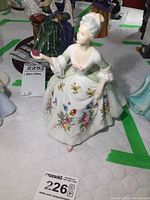 Front view of Royal Doulton Diana figurine showing detailed floral dress and hand holding a flower.