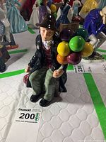 Front view of Royal Doulton Balloon Man figurine showing the man seated holding colorful balloons.