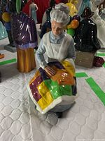 Front view of the Royal Doulton figurine showing the woman sewing a patchwork quilt with colorful fabric pieces.