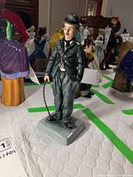 Front view of the full figurine showing face, bowler hat, suit and cane