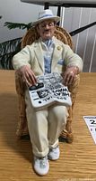 Front view of Royal Doulton porcelain figurine 'Taking Things Easy' depicting seated man with newspaper and glasses, detailed paint and colors visible.