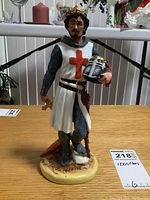 Front view of Royal Doulton Richard The Lionheart figurine showing detailed paint and sculpt of face, crown, tunic with red cross, sword and helmet.