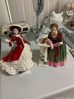 Both Royal Doulton figurines on a table: Victorian Christmas and Florence Nightingale, showing general appearance and condition.