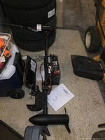 Overall view of trolling motor, battery, manual and accessories on floor