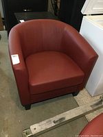 Front view of red vinyl tub chair showing curved back and cushioned seat.