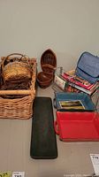 Photo showing woven baskets stacked together, rectangular baking dishes in red and blue, a cast iron skillet, collection of cookbooks in a metal rack, and a green carpet runner.