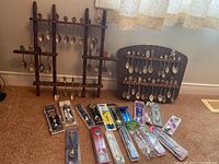 Full lot image showing two wooden spoon display racks and multiple packaged spoons laid out on floor.