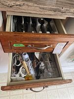 Top drawer with assorted forks, knives, and spoons laid out in utensil organizer
